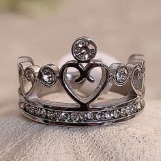 a close up of a ring with a heart on the top and diamonds in the middle