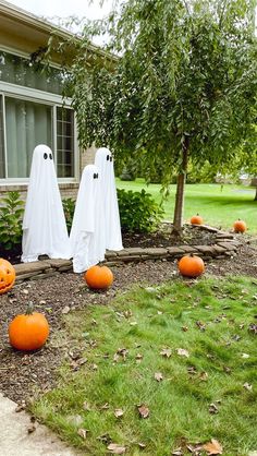 halloween decorations in front of a house with ghost heads and pumpkins on the ground