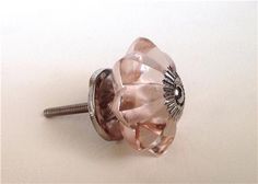 a close up of a pink glass knob on a white surface with a screw in the middle