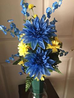 a vase filled with blue and yellow flowers on top of a wooden table next to a door