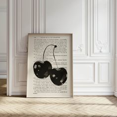 an open book with two cherries on it sitting in front of a white wall