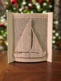 an open book with paper cut out to look like a sailboat on the pages