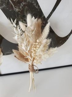 dried flowers are tied up in a vase on a table top with a black and white design behind it