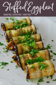 stuffed eggplant rolls on a white plate with garnish