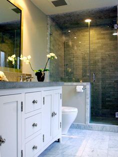 a white toilet sitting under a bathroom mirror next to a walk in shower and sink