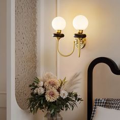 a vase filled with flowers sitting on top of a table next to a wall light