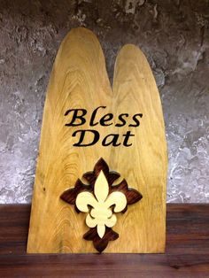 a wooden plaque with a fleur de lis on it that says,'bless dat '