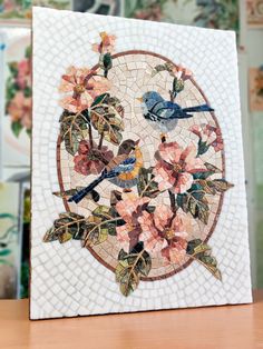 a mosaic tile with birds and flowers on the bottom is displayed in front of a wall