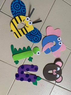 some cut out animals are sitting on the tile floor in front of a tiled wall