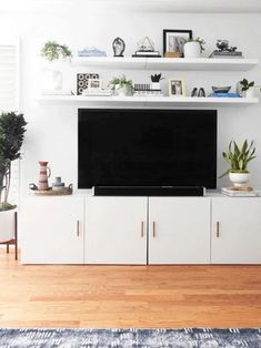 a flat screen tv sitting on top of a white entertainment center in a living room