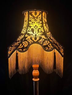 a lamp that is sitting on top of a wooden stand with tasseled lampshades