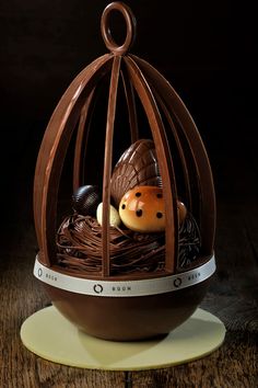 a chocolate bird in a cage on a wooden table