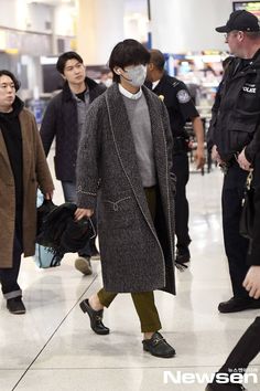 a man wearing a face mask while walking through an airport with other people in the background