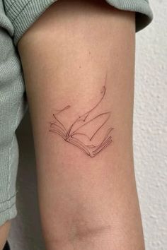 a woman's arm with a tattoo on it and an open book in the middle