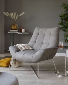 a grey chair sitting in a living room next to a table with candles on it