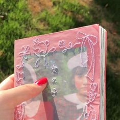 a person holding up a pink book with pictures on the front and back cover in their hand