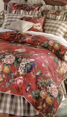 a bed with red and white flowers on the comforter, pillows and pillow cases