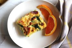 an omelet with spinach, bacon and orange slices on a white plate