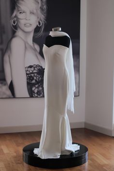 a white dress on display in front of a black and white photo