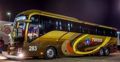 a bus parked in front of a building at night with people standing around the bus