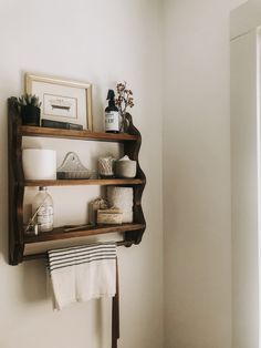 a shelf with towels, candles and other items on it in the corner of a bathroom