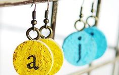 three earrings hanging from hooks with letters on them