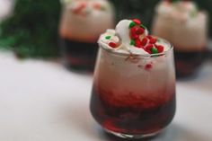 three glasses filled with red liquid and candy canes on top of a white table