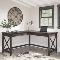 a wooden desk with a laptop on it in front of a large clock and window