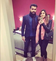 a man and woman taking a selfie in a hotel room with a pink wall