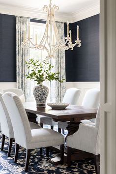 a dining room table with white chairs and a chandelier