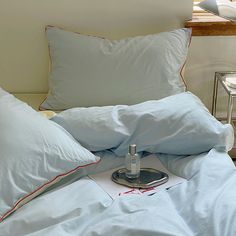 a bed with blue sheets and pillows on top of it next to a table lamp