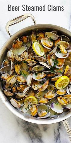 a pan filled with clams on top of a marble counter next to utensils