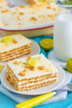 a piece of cake on a plate next to a glass of milk and limes