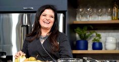 a woman is smiling while preparing food in the kitchen