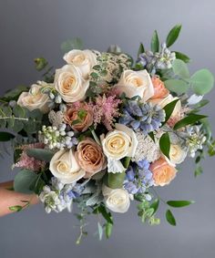 a bouquet of flowers is being held by someone's hand on a gray background