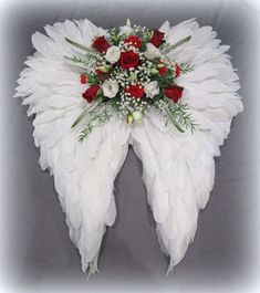 a white angel wing with red roses and baby's breath