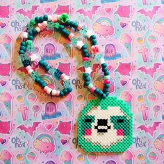 a green beaded necklace with a white and black panda face on it, sitting next to a colorful background