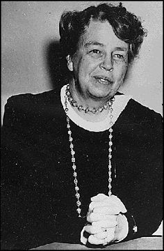 an old black and white photo of a woman with beads on her necklace sitting at a table