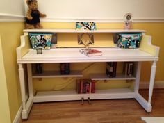 a white desk with books and vases sitting on it's shelf next to a teddy bear