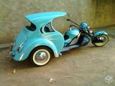 a blue motorcycle with a side car attached to it's back end, parked in front of a concrete wall