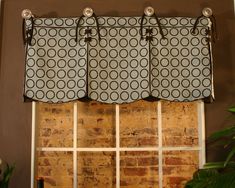 a window curtain with circles on it in front of a brick wall and potted plant