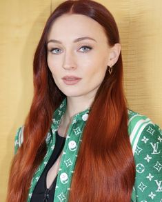 a woman with long red hair wearing a green shirt