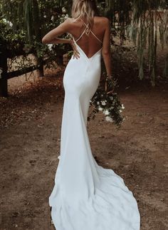 a woman in a white wedding dress is standing outside with her back to the camera