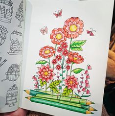 a person holding up a book with flowers and butterflies in the pages next to them