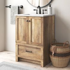 a bathroom with a sink, mirror and basket on the floor in front of it