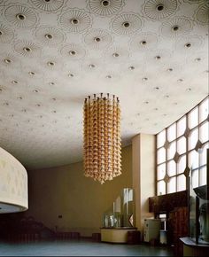 a chandelier hanging from the ceiling in a room with large windows and circular lights