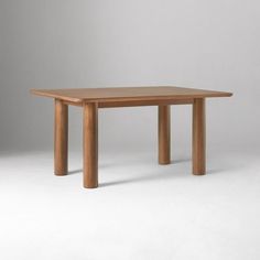 a wooden table sitting on top of a white floor next to a gray wall in an empty room