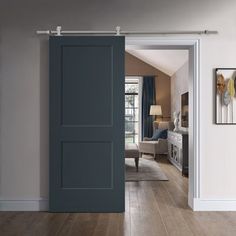 an open door leading to a living room with hardwood floors and white walls, along with blue curtains