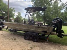 a boat parked on the side of a dirt road next to a truck and trailer