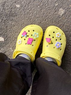 a pair of yellow shoes with flowers on them are sitting on the ground in front of someone's feet